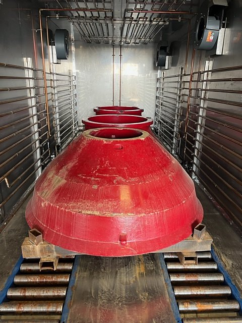 Red crusher mantles lined up on the roller bed inside a DCI chamber
