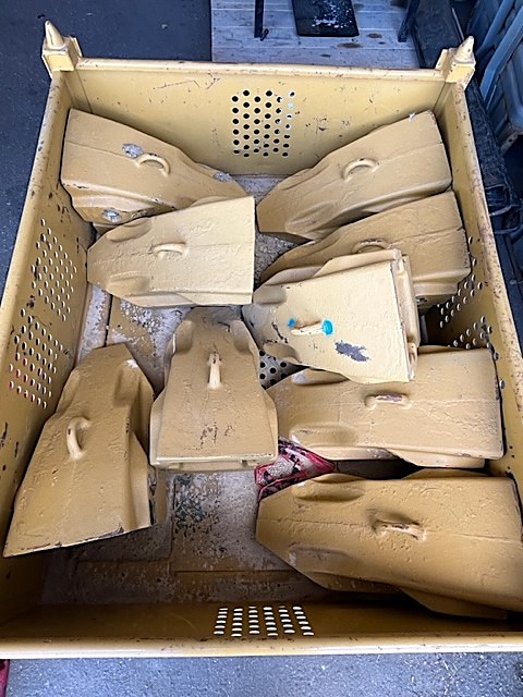 Yellow shovel teeth in a steel bin